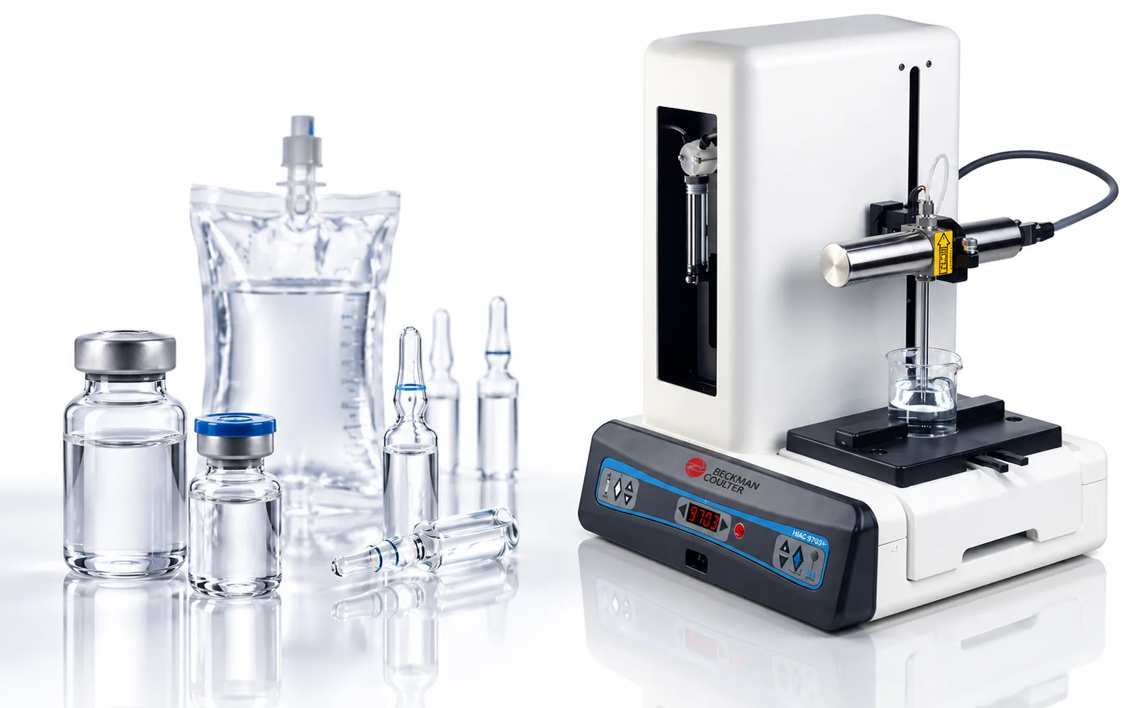 Contador de partículas HIAC 9703+ de Beckman Coulter junto a viales, ampollas y una bolsa de infusión para el análisis de medicamentos inyectables.